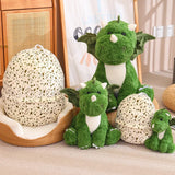 Green dinosaur plush toys in various sizes next to a speckled dragon egg-shaped pillow.