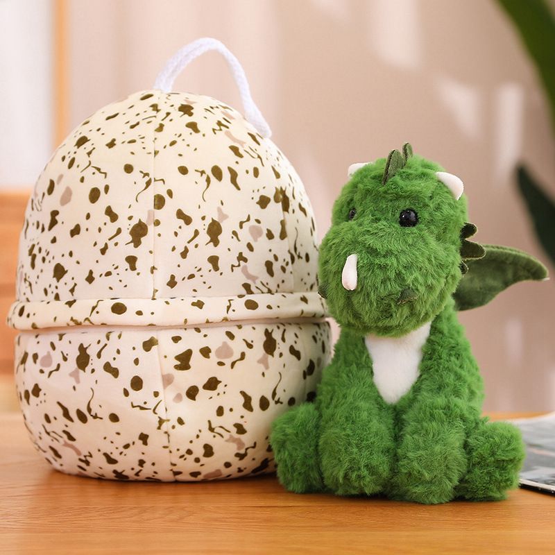 A green dinosaur plush toy sits next to a speckled egg-shaped pillow on a wooden surface.