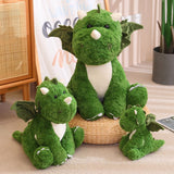 Three green plush dinosaur toys with wings, sitting on a woven mat in a cozy room setting.