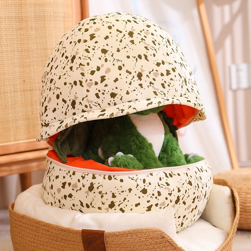 Plush dinosaur toy peeking out from a speckled dragon egg-shaped pillow.