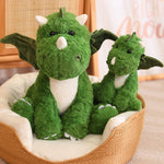 Green plush dinosaur with wings and a smaller companion, sitting in a cozy basket.