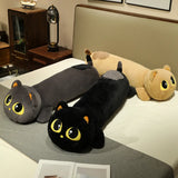 Three long cat plush pillows in gray, black, and beige, lying on a bed with a neutral background.