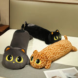 Three long plush pillows shaped like cats and a giraffe, with large eyes, resting on a bed.