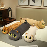 Four long plush pillows resembling cats and a giraffe, arranged on a bed with decorative items nearby.
