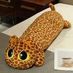 Long plush pillow shaped like a cat with a giraffe pattern and large eyes, resting on a bed.