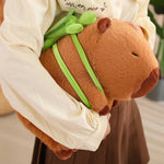 Person holding a capybara plush with a small green turtle on its back.