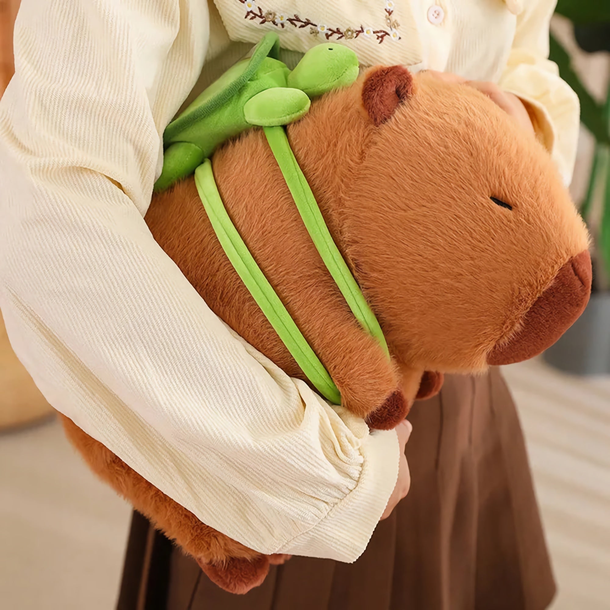 Person holding a capybara plush with a small green turtle on its back.