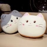 Two plush cat-shaped pillows, one gray and white, the other cream and orange, resting on a beige surface.