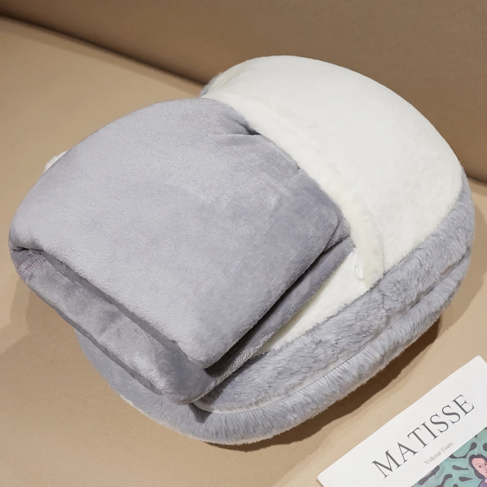 A folded gray and white blanket set resting on a surface next to a magazine.