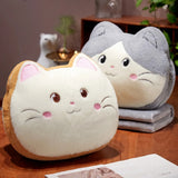 Two plush cat-shaped pillows with smiling faces on a wooden table.