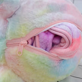 Close-up of a pastel-colored plush fabric with a pink zipper partially open, revealing a rolled-up blanket inside.