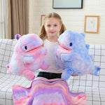 Girl holding two plush dinosaur toys with a colorful blanket on her lap.