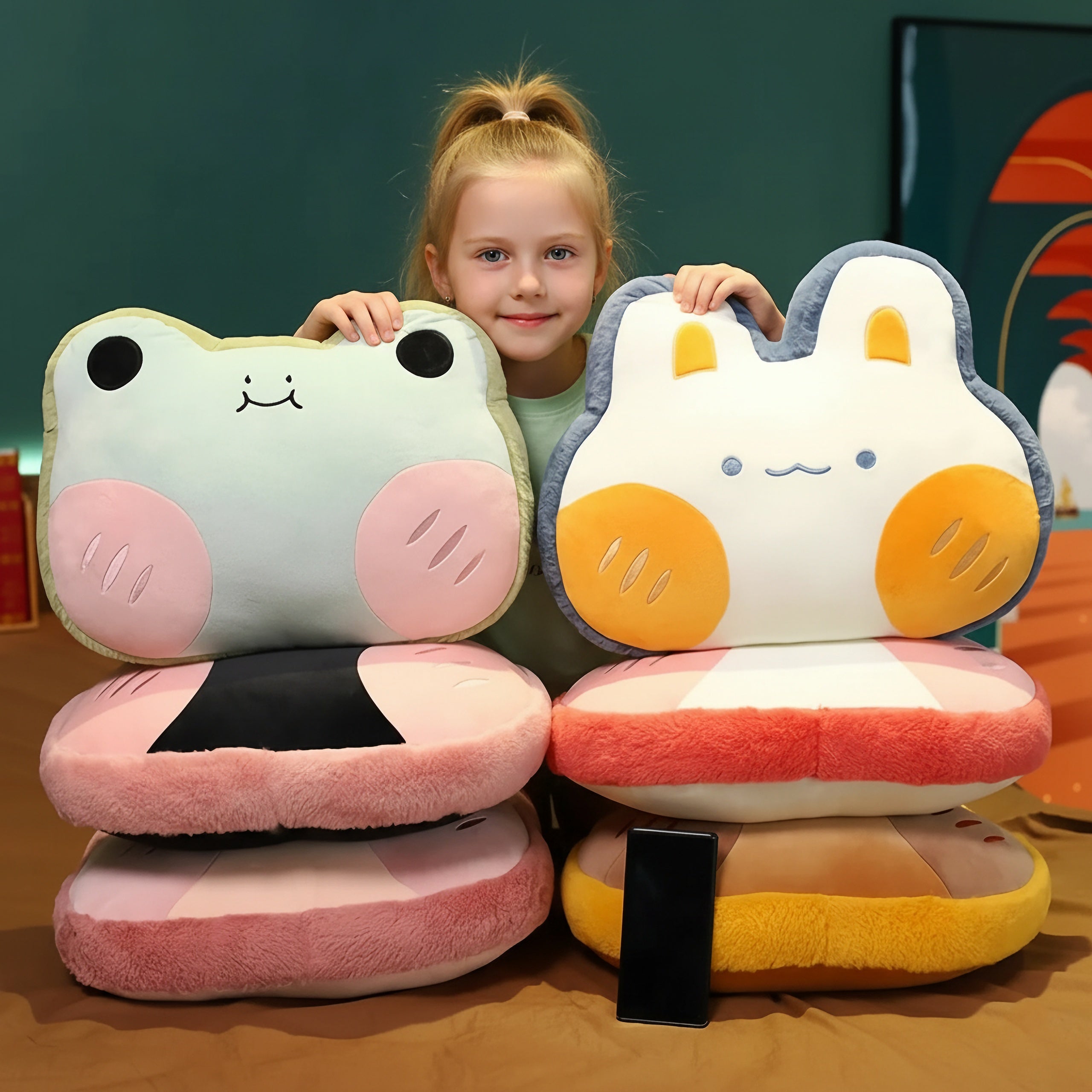 Child holding plush pillows shaped like a frog and a bunny, with matching blankets stacked below.