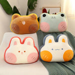 Four plush pillows shaped like animals with cute faces on a blanket.