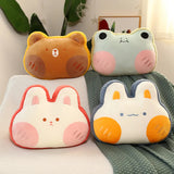 Four plush pillows shaped like animals with cute faces on a blanket.
