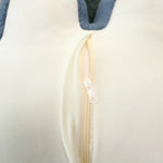 Close-up of a cream-colored fabric with a zipper and blue edge.