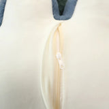 Close-up of a cream-colored fabric with a zipper and blue edge.