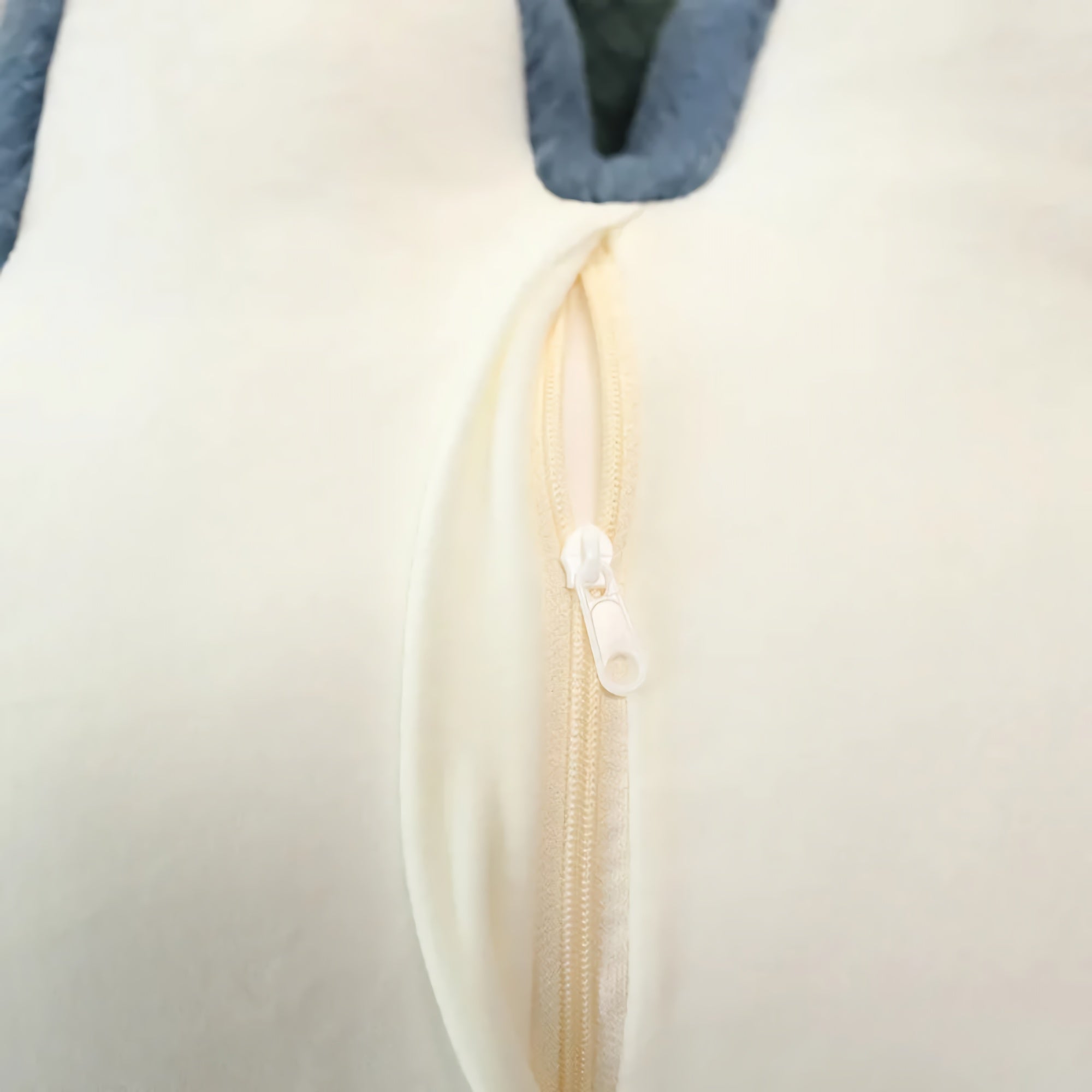 Close-up of a cream-colored fabric with a zipper and blue edge.