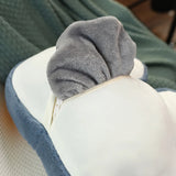 A plush pillow with a gray fabric top and a zipper, partially revealing a soft blanket inside.