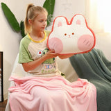 Girl holding a pink and white plush pillow shaped like a bunny, sitting with a pink blanket.