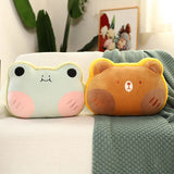 Two plush pillows shaped like a frog and a bear, resting on a textured blanket.