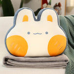 Plush pillow shaped like a bunny with orange cheeks, resting on a folded gray blanket.