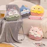 A gray blanket drapes over a chair beside plush pillows shaped like animals in pastel colors.
