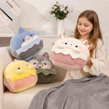 A girl holds a plush pillow shaped like a cake, surrounded by other colorful plush pillows on a couch.