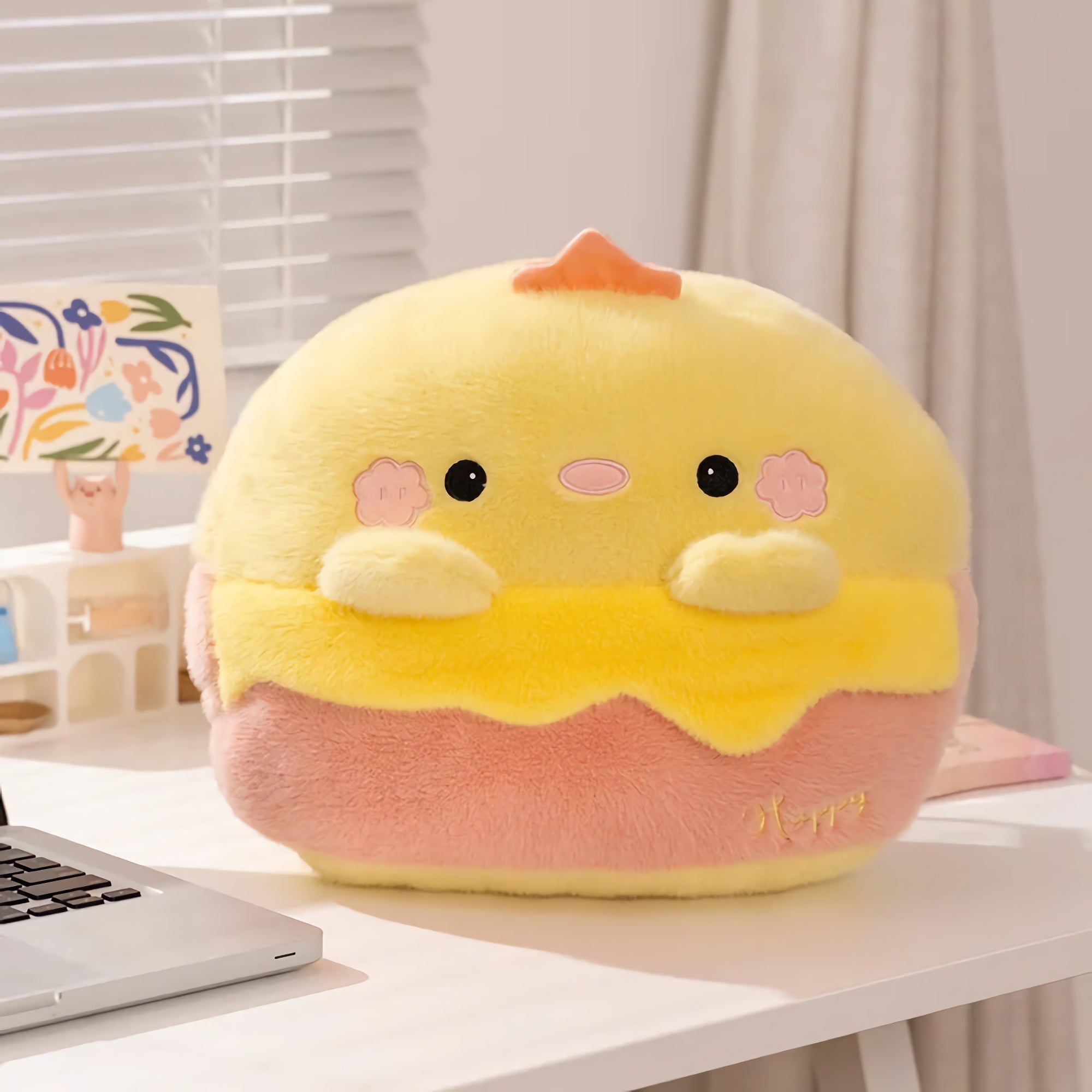 Plush pillow shaped like a cute yellow and pink character on a desk.