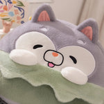 Plush pillow with a cute animal face, gray ears, and a green blanket.