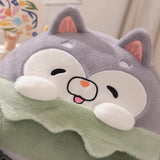 Plush pillow with a cute animal face, gray ears, and a green blanket.