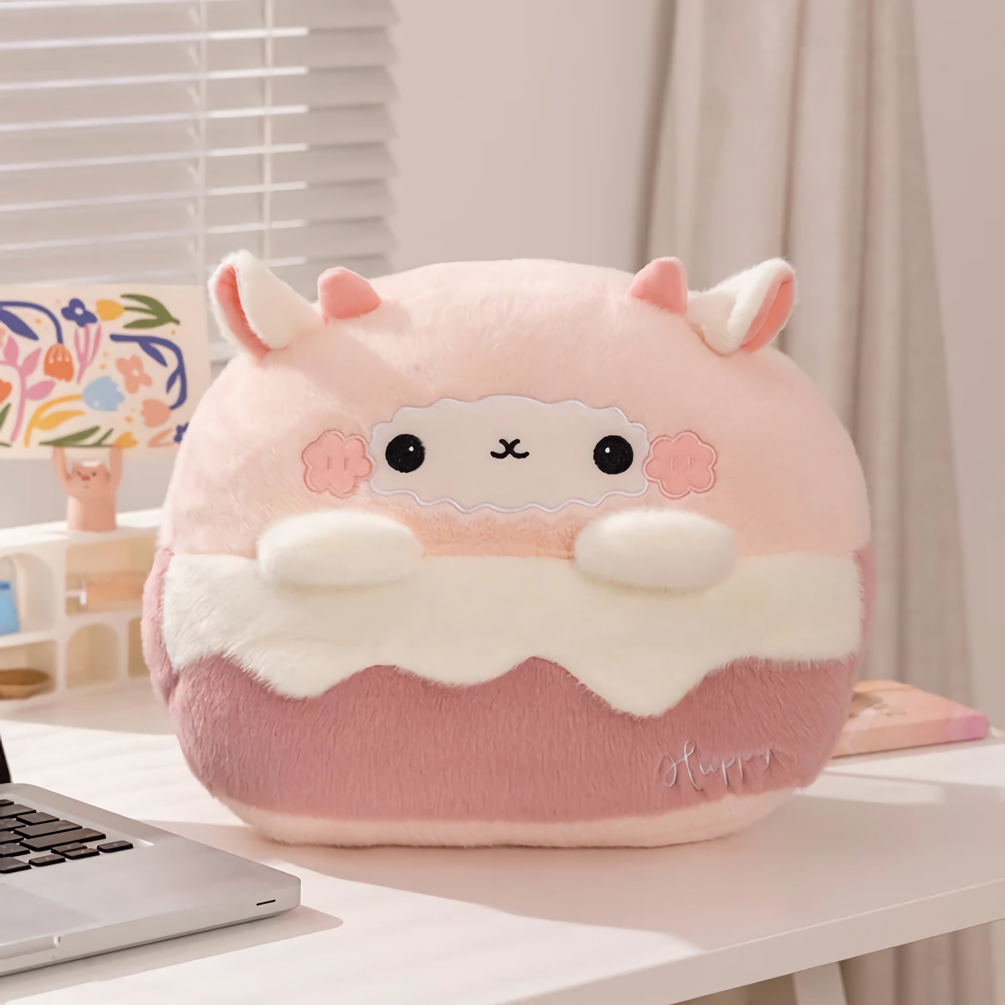 A plush pillow shaped like a cute dessert with a smiling face, pink and white colors, and small ears.