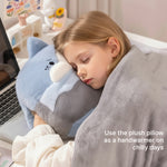 A child sleeps with a plush pillow while wrapped in a soft blanket, resting on a desk with a laptop.
