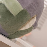 Plush pillow with a soft, textured surface in green and gray colors, resting on a white surface.