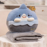A plush pillow shaped like a blue mountain with a crown, resting on a folded gray blanket.
