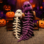 A child and an adult wear dinosaur skeleton plush hoods and spines, sitting in front of carved pumpkins.