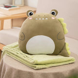 Plush dinosaur pillow and matching green blanket on a table.