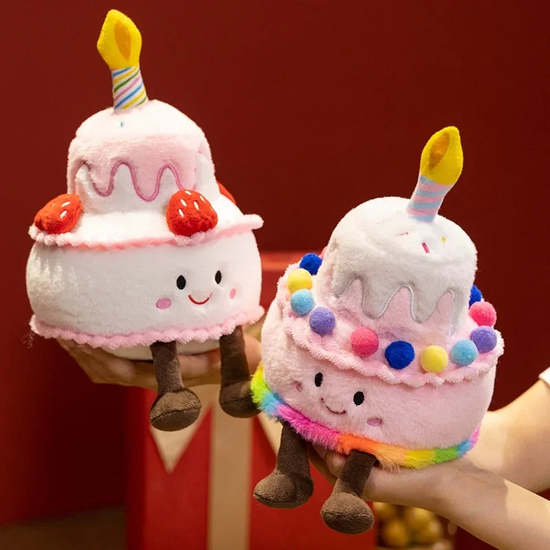 Two plush birthday cake pillows with candles and smiling faces, held by hands against a red background.