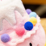 Kawaii plush pillow shaped like a birthday cake, featuring colorful pom-poms and a white frosting top.