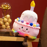 Kawaii plush pillow shaped like a birthday cake with a candle, colorful frosting, and a smiling face.