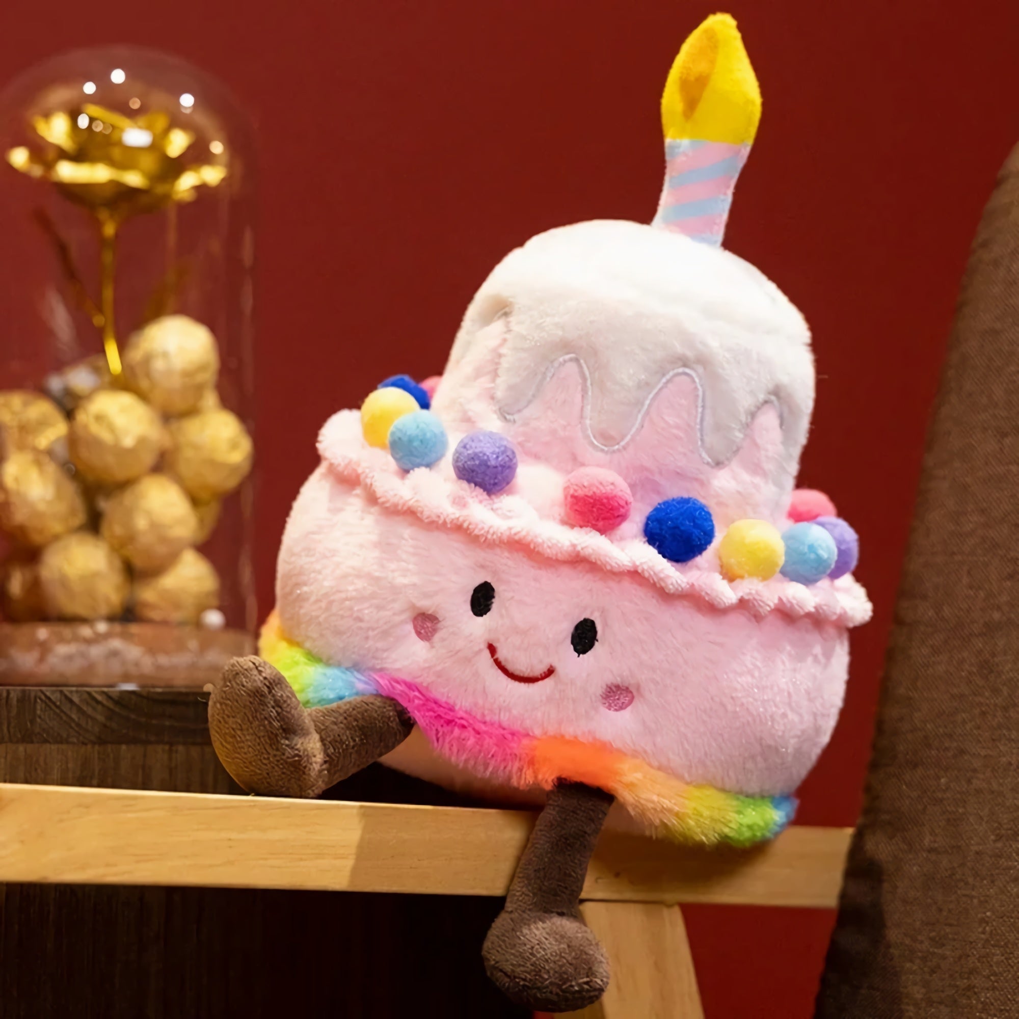 Kawaii plush pillow shaped like a birthday cake with a candle, colorful frosting, and a smiling face.