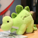 Green plush dinosaur toy with spikes, sitting on a wooden surface next to a magazine.