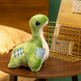 Green plush dinosaur with large eyes and patchwork details, sitting on a wooden table next to a wire basket.
