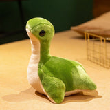 Plush toy of a green Loch Ness monster with large eyes and a soft body, sitting on a flat surface.