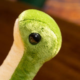 Close-up of a green plush dinosaur with a soft texture and large black eyes.