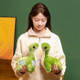 A person holds two green plush dinosaur toys, smiling and looking down at them, with a green background.