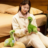 A person sits on a bed holding two green plush dinosaur toys in a cozy room setting.