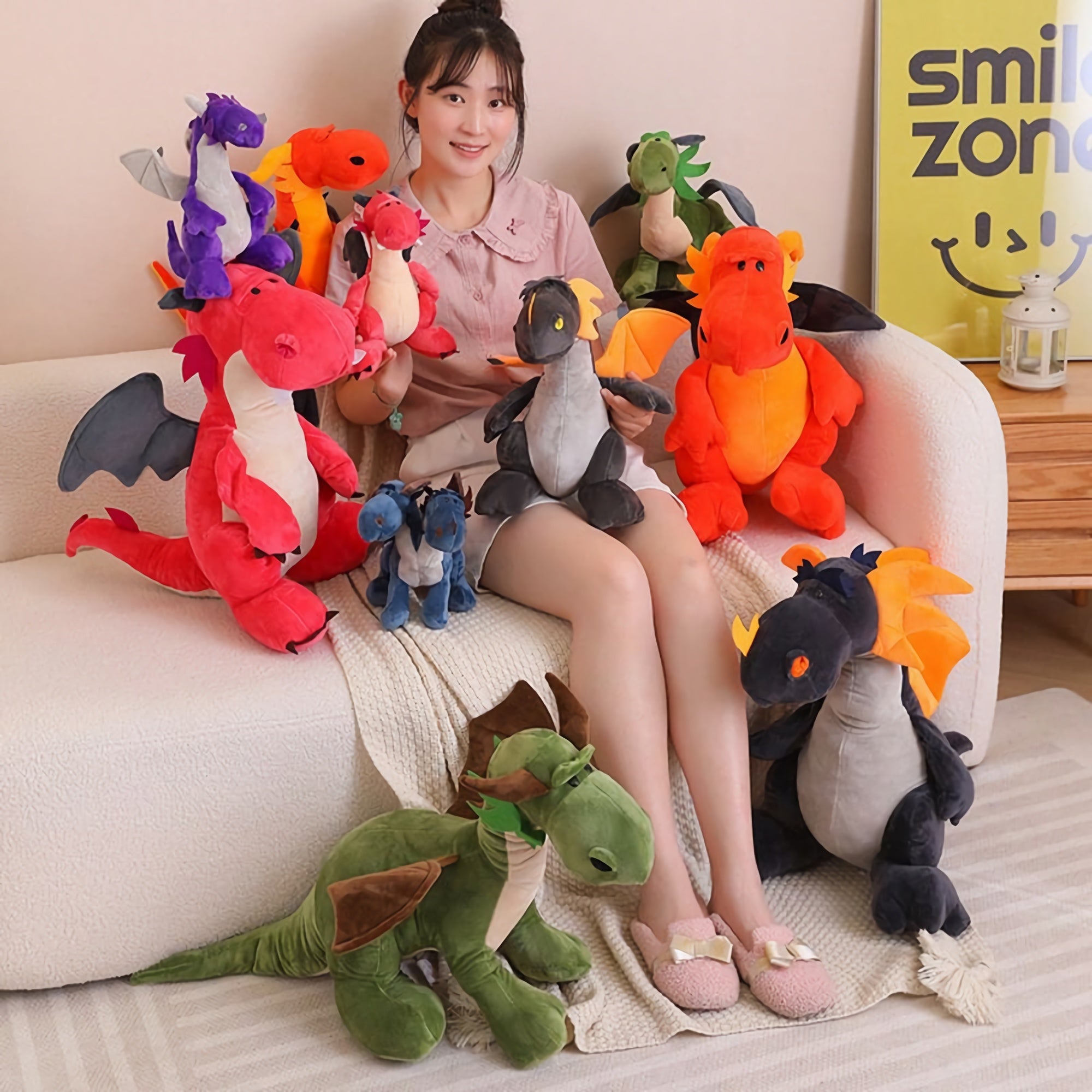 A person sitting on a couch surrounded by colorful plush dragon and dinosaur toys.