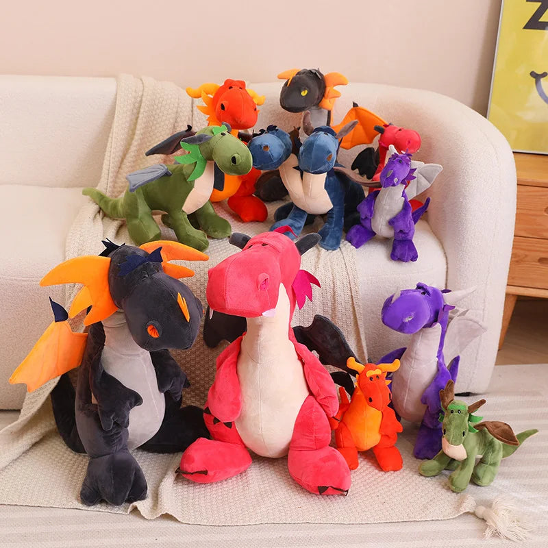 A variety of colorful plush dragon and dinosaur toys arranged on a couch with a blanket.