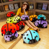 A person sits among colorful squishy ladybug plush pillows in a cozy indoor setting.